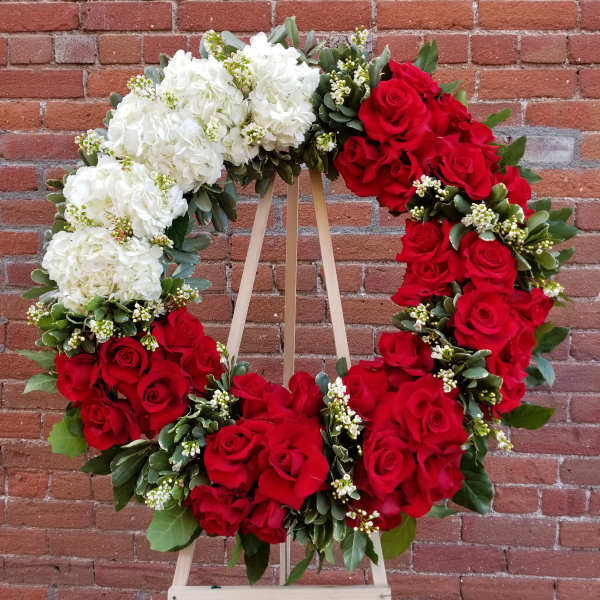 Heart-shaped wreath of red and white roses on a wooden easel