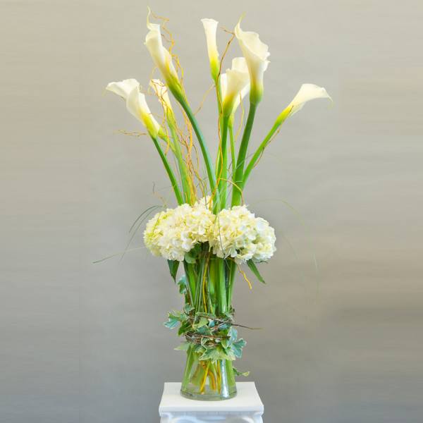 Tall white calla lily arrangement in a glass vase