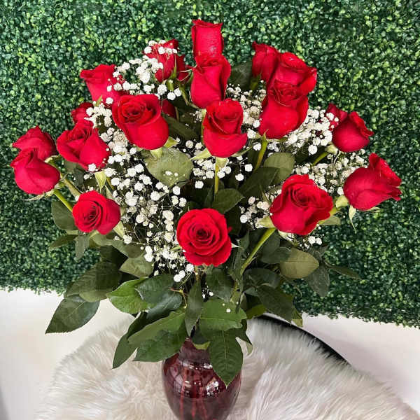 Red roses with white baby's breath in a red glass vase