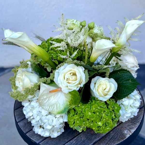 White floral arrangement with roses, calla lilies, and hydrangeas
