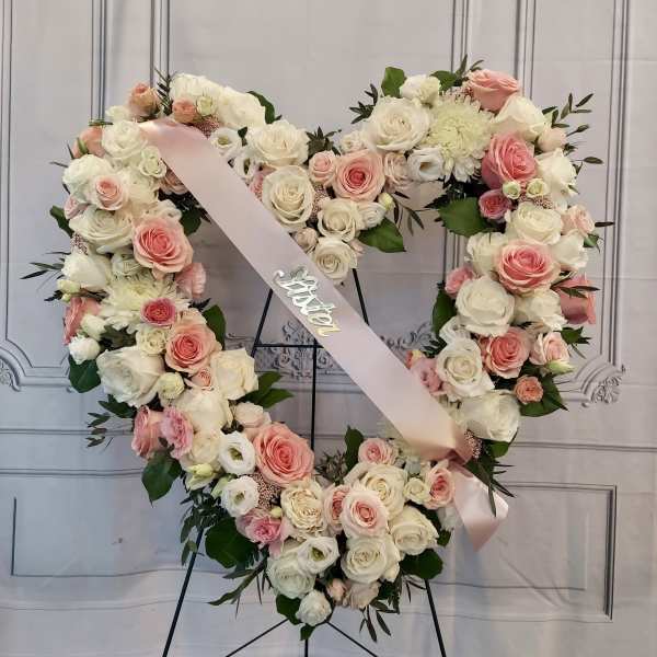Heart-shaped floral wreath of pink and white roses with a pink ribbon