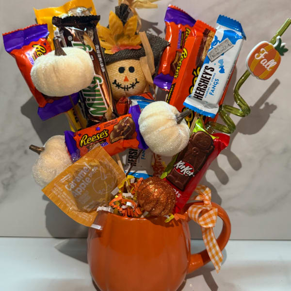 Candy bouquet in an orange mug with pumpkin decorations and ribbon