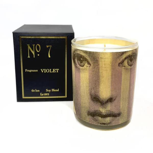 Violet-scented candle in a glass jar beside a black box