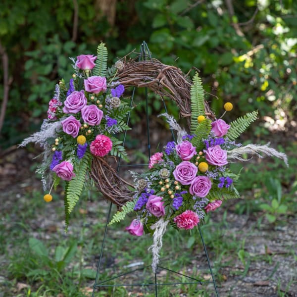 Floral wreath with pink roses and purple flowers on a twig frame