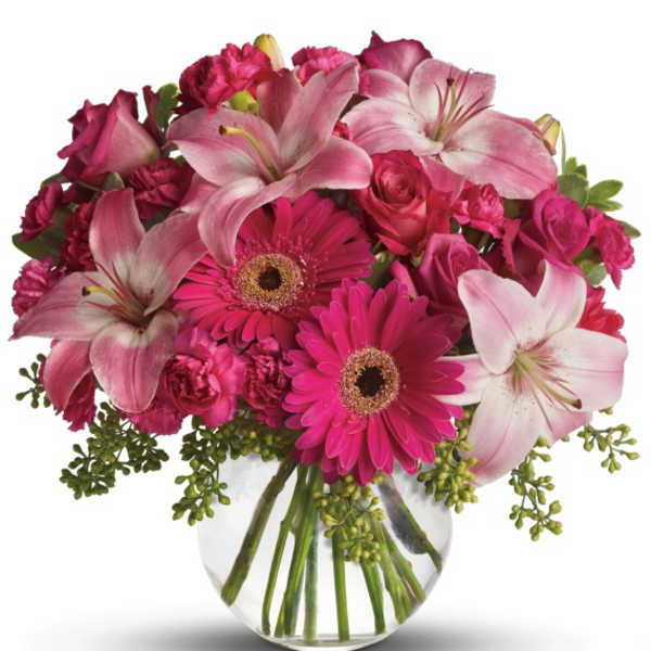 Pink lilies, gerbera daisies, and roses in a clear glass vase