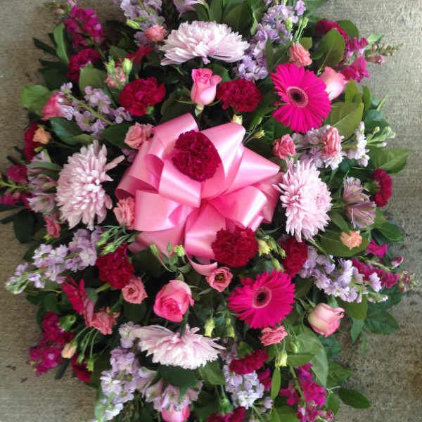 Round bouquet of pink and purple flowers with a large pink bow