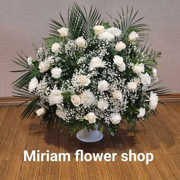 Large white floral arrangement in a low pedestal vase