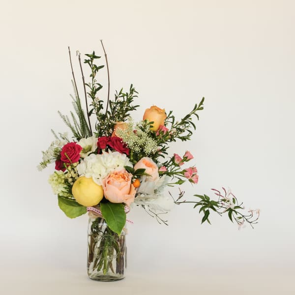 Mixed bouquet in a clear glass jar with roses and white blooms