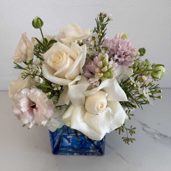 Bouquet of white roses and pale pink flowers in a blue glass vase