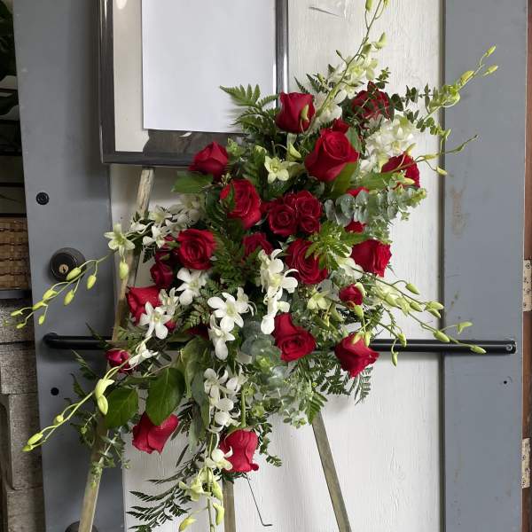Standing floral spray with red roses and white orchids on an easel