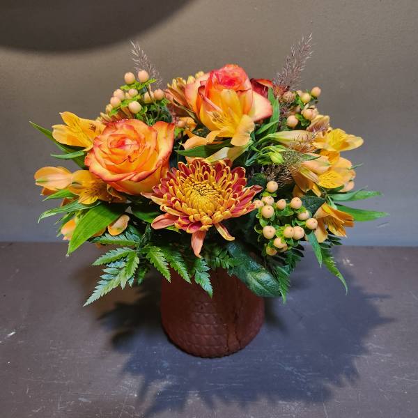 Orange roses and yellow chrysanthemums in a brown vase