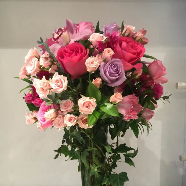 Tall bouquet of pink and lavender roses in a clear glass vase
