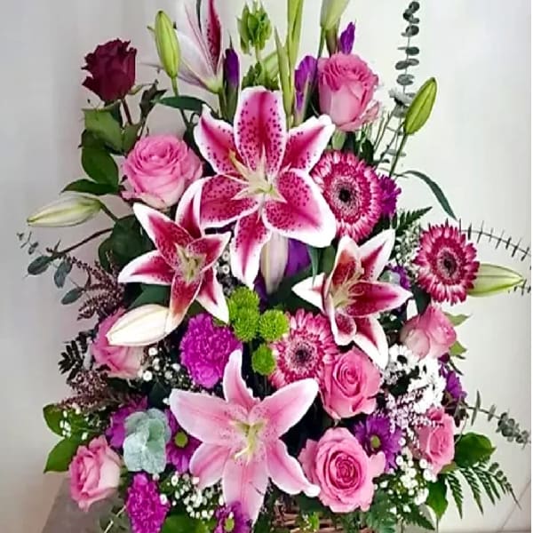 Pink lilies and roses in a wicker basket arrangement