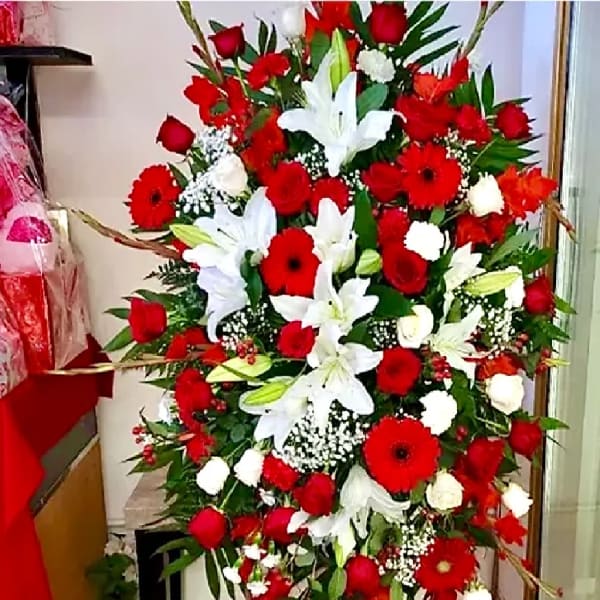 Large standing spray of red and white flowers on an easel