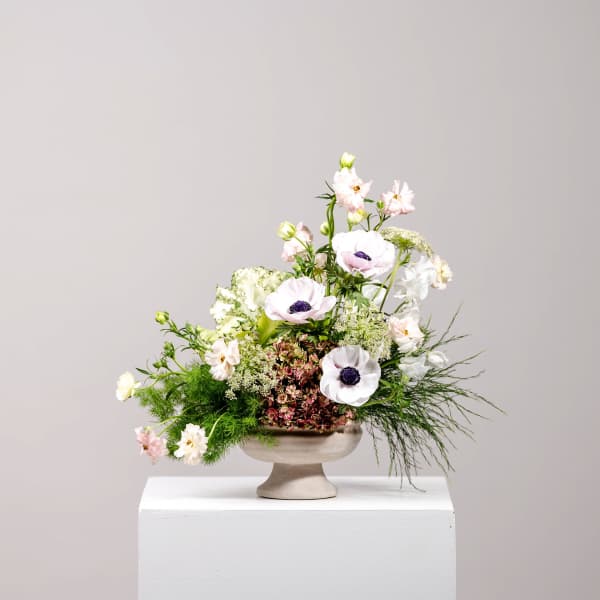 Pastel floral arrangement in a pedestal vase with white and pink blooms