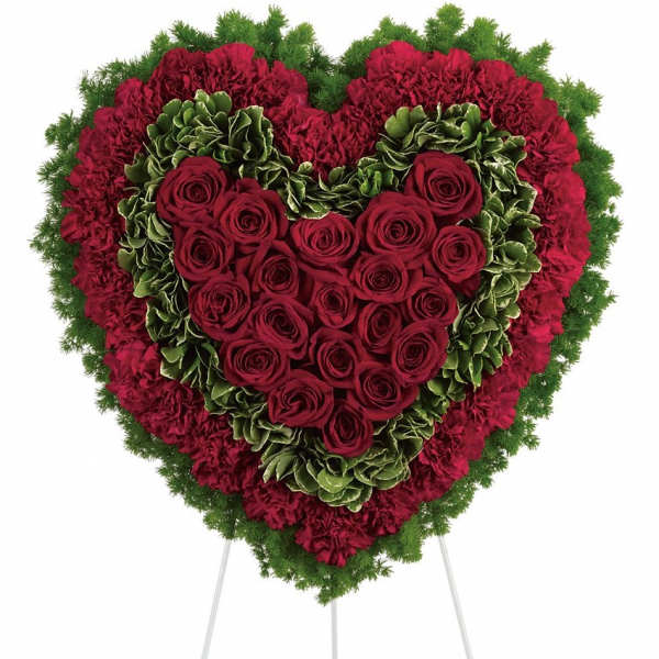 Heart-shaped floral tribute with red roses and carnations on a stand