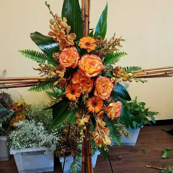 Tall floral arrangement with orange roses and gerbera daisies on bamboo supports