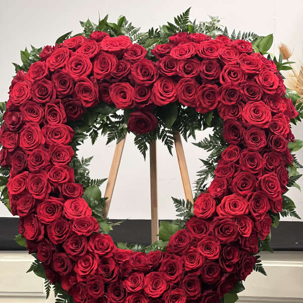 Heart-shaped wreath of red roses on a wooden easel