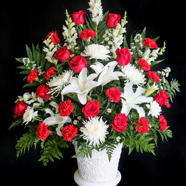 Red roses and white lilies in a white pedestal vase