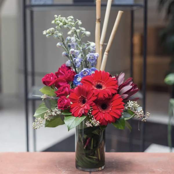 Red gerbera daisies and roses in a clear glass vase