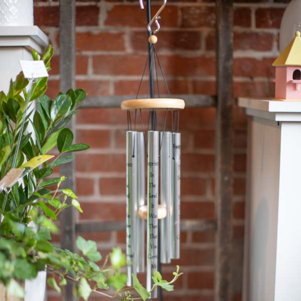Hanging silver wind chime with a wooden top and black cords