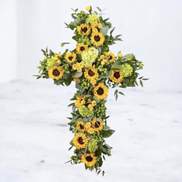 Sunflower cross arrangement with green filler on a white background