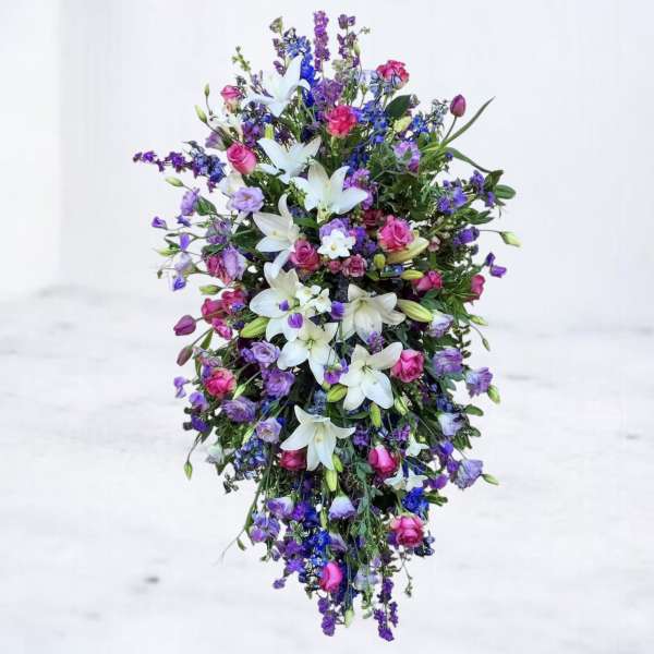 Tall cascading arrangement of white lilies with pink and purple blooms in a teardrop shape