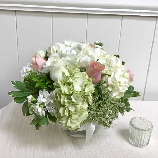 White and pale pink bouquet with hydrangeas and roses in a low container