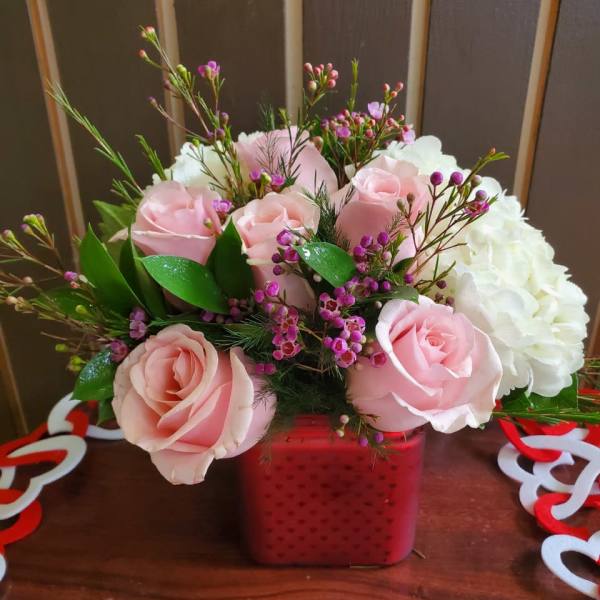 Pink roses and white hydrangea in a red square vase