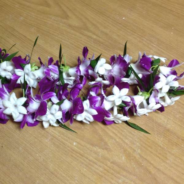 Purple and white flower garland laid on a wooden surface