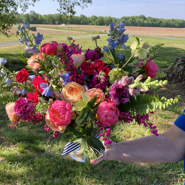 Colorful bouquet of roses, peonies, and blue flowers in a glass vase