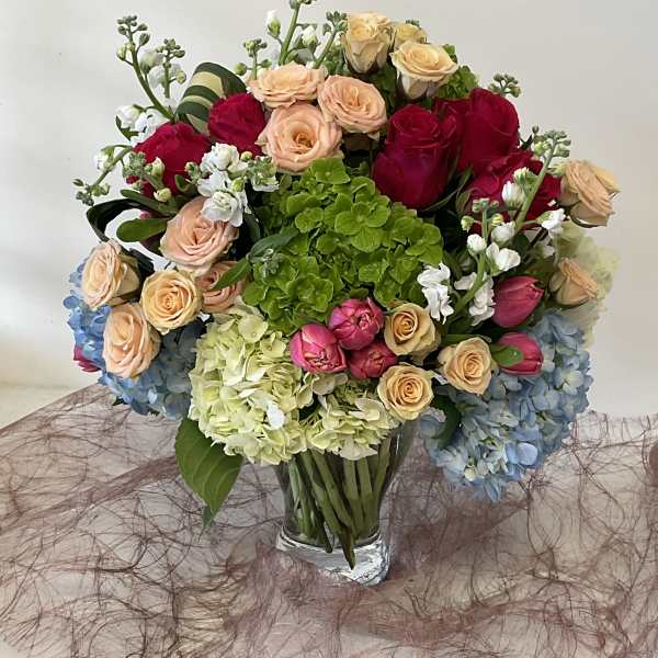 Mixed bouquet of roses and hydrangeas in a clear glass vase