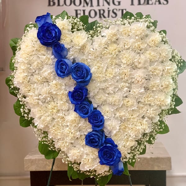 Heart-shaped white floral arrangement with a diagonal line of blue roses