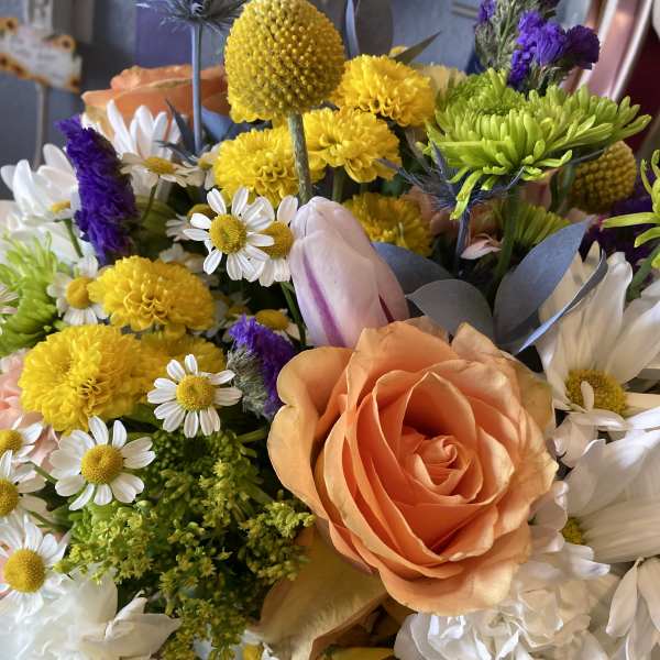 Mixed bouquet with peach roses, yellow blooms, and white daisies
