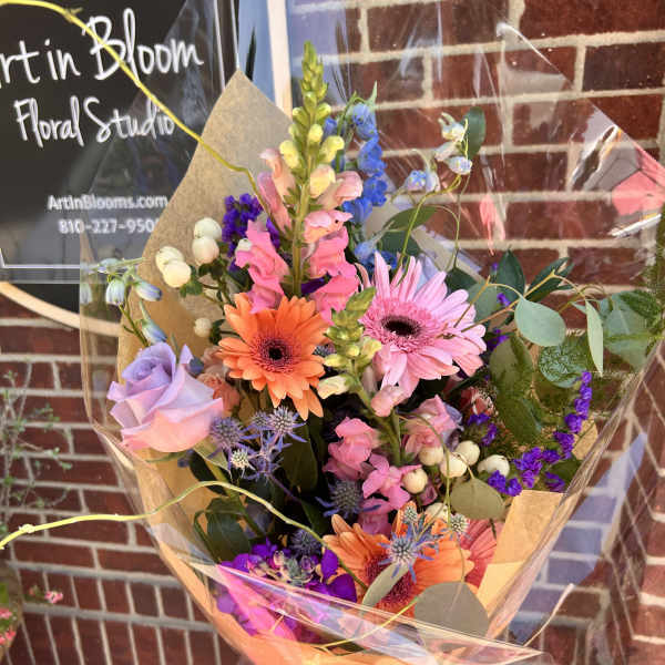 Colorful mixed bouquet with gerbera daisies, roses, and snapdragons in clear wrap
