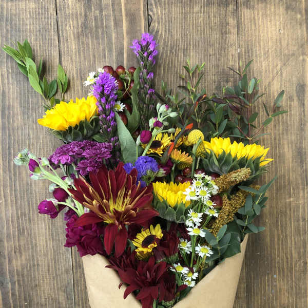 Bouquet of mixed flowers wrapped in brown paper with a red ribbon