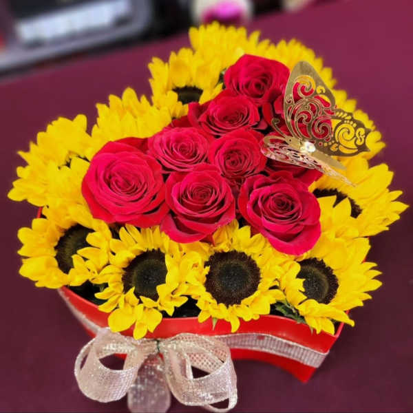 Red roses arranged with yellow sunflowers in a heart-shaped box