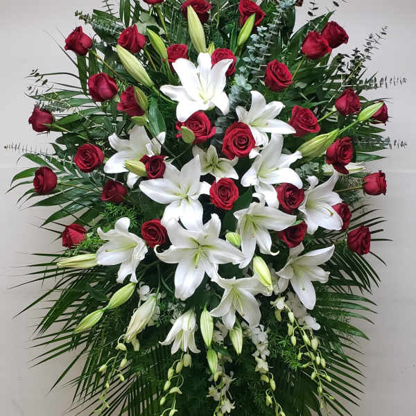 Tall standing spray of red roses and white lilies displayed on an easel