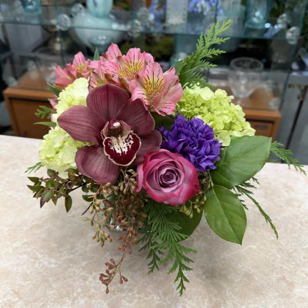 Mixed bouquet with pink, purple, and green flowers in a low vase