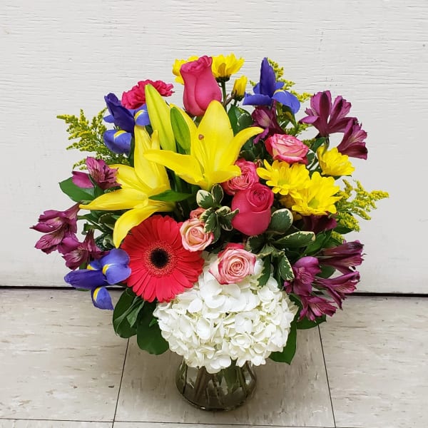 Mixed bouquet with lilies, roses, gerbera daisies, and hydrangea in a glass vase
