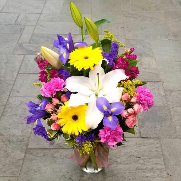 Colorful mixed bouquet with lilies, gerbera daisies, and roses in a glass vase