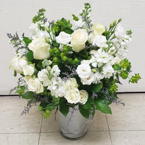 White roses and white stock in a glass vase with green accents
