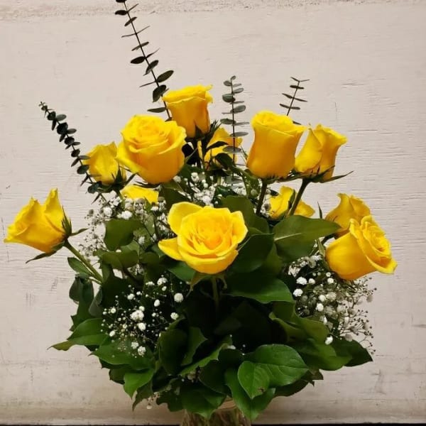 Yellow roses arranged in a clear glass vase with baby's breath