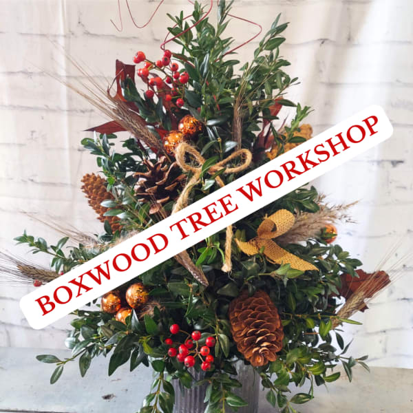 Holiday arrangement with pinecones, red berries, and gold ornaments in a container