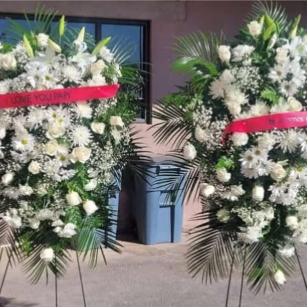 Two white funeral standing sprays with pink ribbons on easels