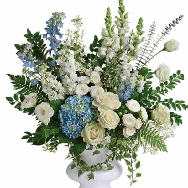 White and blue floral arrangement in a white pedestal vase