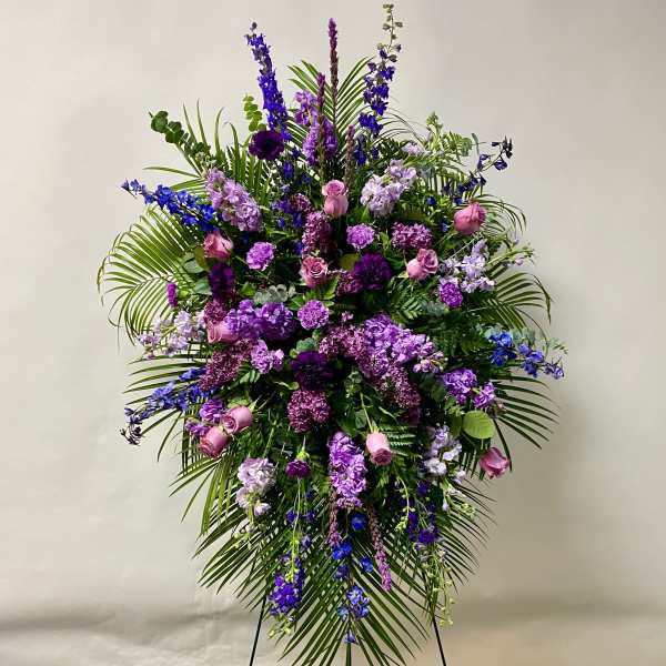 Large standing floral spray with purple and pink flowers on a tripod easel