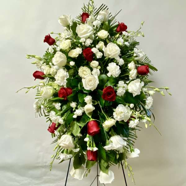 Standing spray of red and white roses with white carnations on an easel