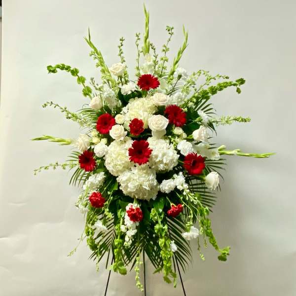 Standing floral spray with red and white flowers on a black easel