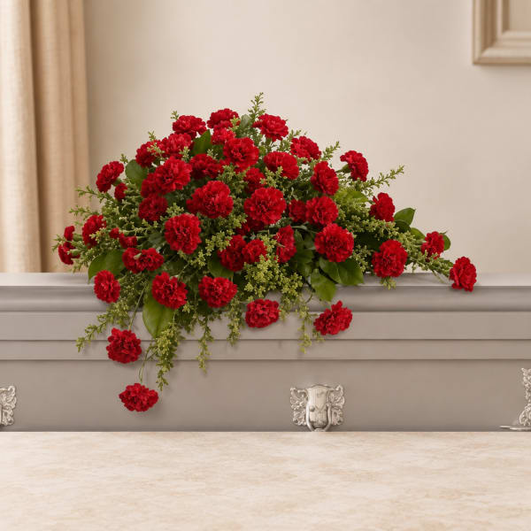 Red carnation arrangement on a casket with green foliage